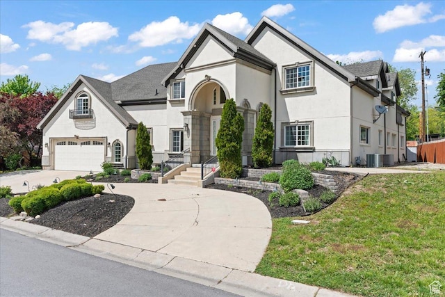 view of front of property with an attached garage, driveway, stucco siding, a front lawn, and cooling unit