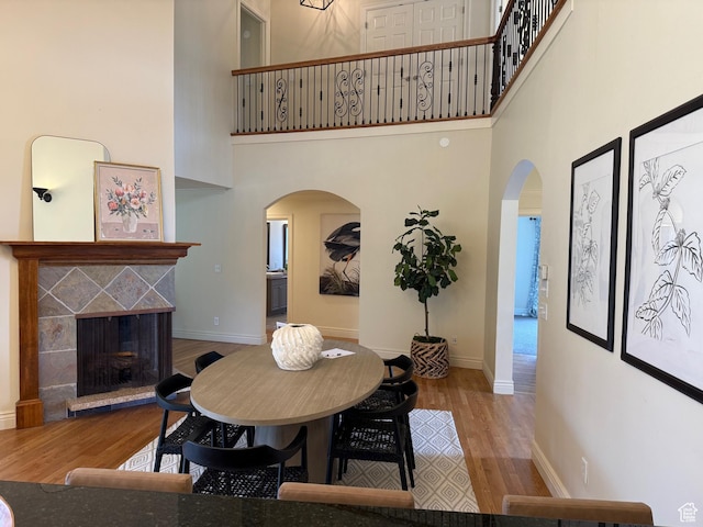 2765 E Blue Spruce Dr, Holladay, UT 84117 - dining room featuring arched walkways, wood finished floors, a high ceiling, baseboards, and a tile fireplace