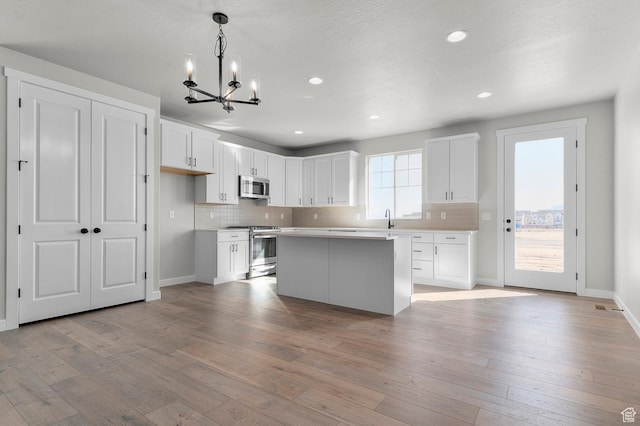 3707 W 2600 N, Lehi, UT 84043 - kitchen with stainless steel appliances, white cabinetry, decorative backsplash, and light wood finished floors