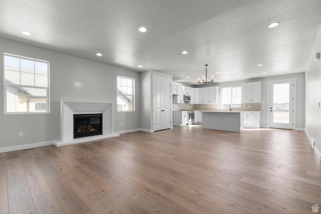 3707 W 2600 N, Lehi, UT 84043 - unfurnished living room featuring a glass covered fireplace, plenty of natural light, and wood finished floors