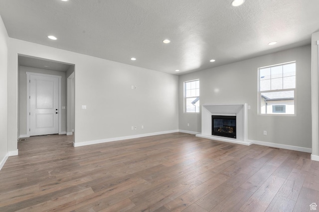 3707 W 2600 N, Lehi, UT 84043 - unfurnished living room featuring a glass covered fireplace, baseboards, wood finished floors, and recessed lighting