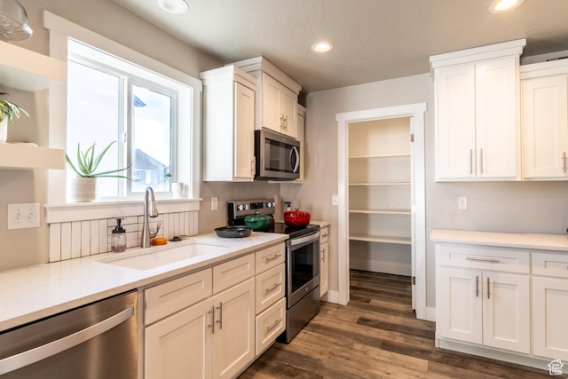 kitchen with appliances with stainless steel finishes, light countertops, a sink, and white cabinetry