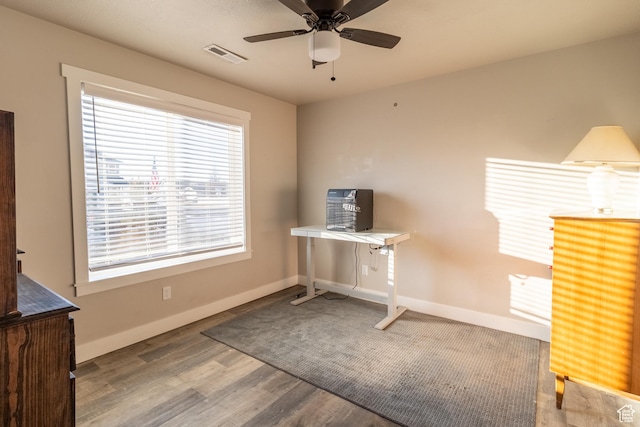 unfurnished office with baseboards, visible vents, ceiling fan, and wood finished floors