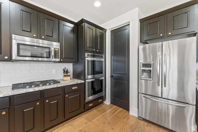 615 N Haystack Mountain Dr, Heber City, UT 84032 - kitchen with dark brown cabinetry, tasteful backsplash, light wood-style flooring, appliances with stainless steel finishes, and light stone countertops