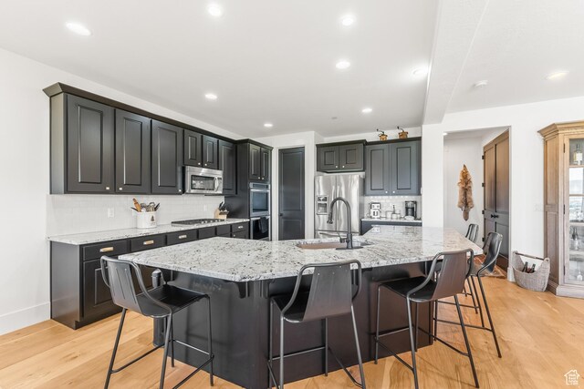 615 N Haystack Mountain Dr, Heber City, UT 84032 - kitchen featuring light wood finished floors, a large island, a breakfast bar area, dark cabinets, and stainless steel appliances