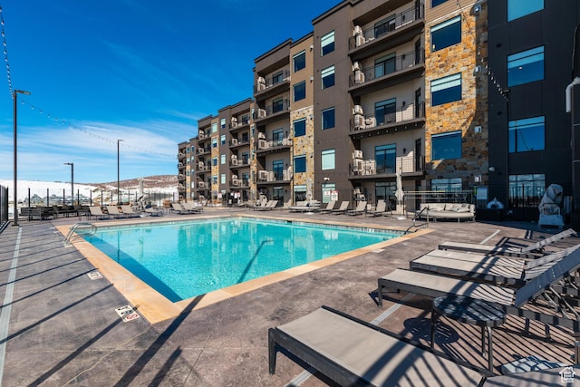 community pool with a patio area and fence