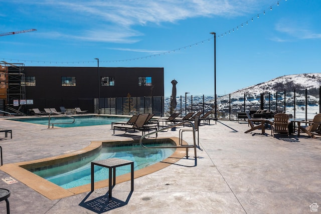 pool with a patio area, a mountain view, and fence