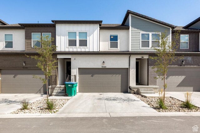 view of property with driveway, an attached garage, and board and batten siding