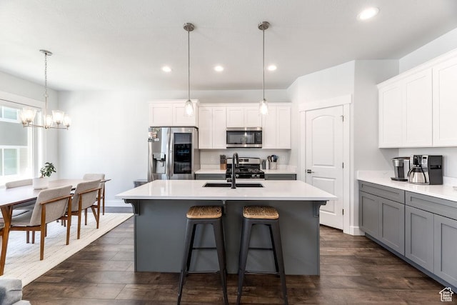 kitchen with stainless steel appliances, dark wood-style flooring, light countertops, and a sink