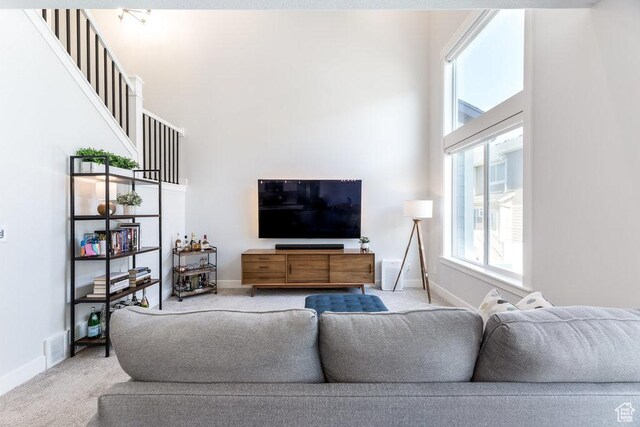 carpeted living area featuring visible vents, a towering ceiling, and baseboards