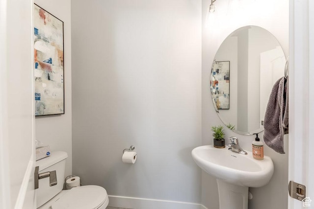 bathroom with baseboards, a sink, and toilet