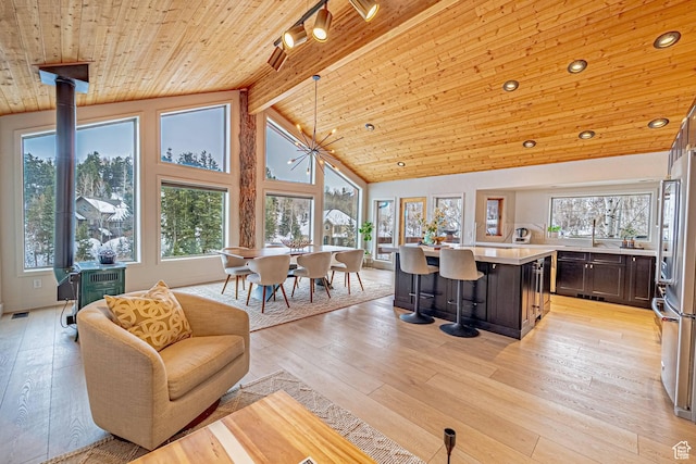 living room featuring high vaulted ceiling, light wood-style flooring, a notable chandelier, wood ceiling, and beam ceiling