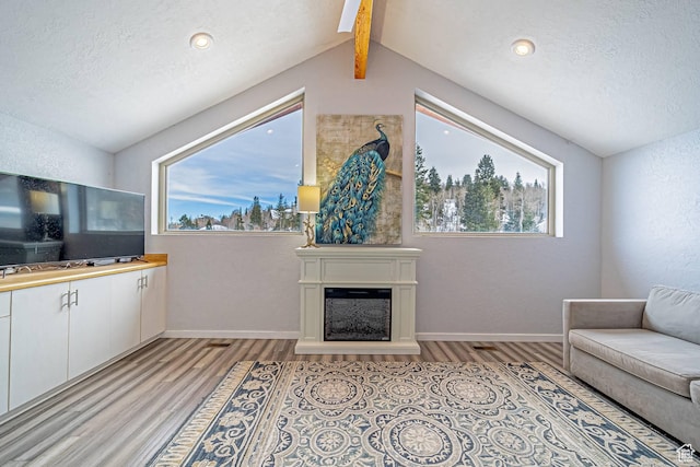 4414 Hidden Cove Rd, Park City, UT 84098 - living room with a fireplace with raised hearth, lofted ceiling with beams, a textured ceiling, baseboards, and light wood-type flooring