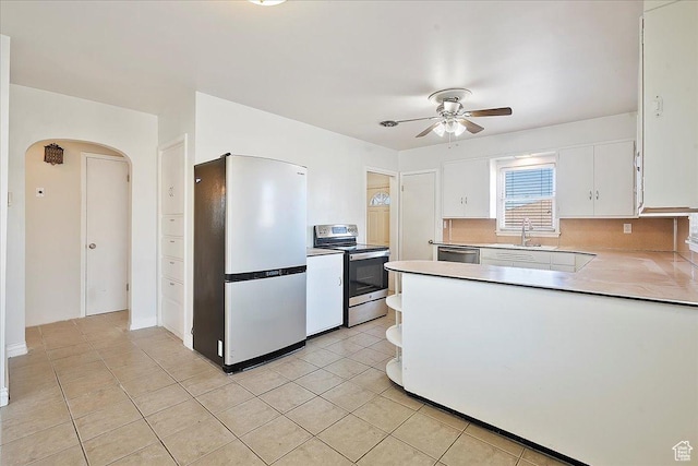 867 33rd St, Ogden, UT 84403 - kitchen with arched walkways, light tile patterned floors, stainless steel appliances, light countertops, and white cabinets