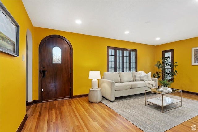 unfurnished living room with light wood finished floors, baseboards, arched walkways, and recessed lighting