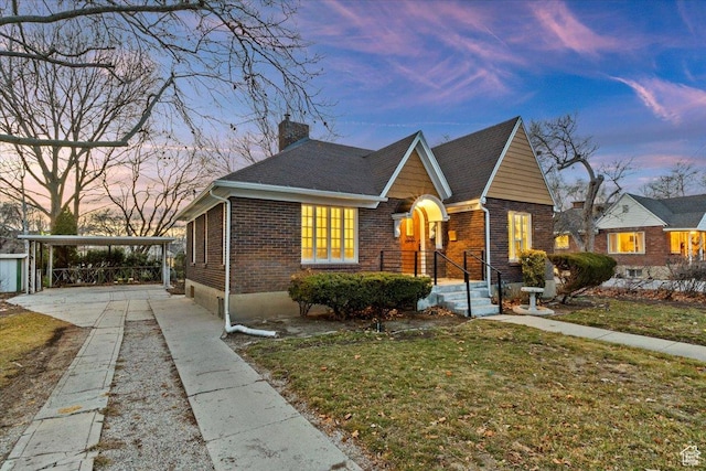 view of front facade featuring concrete driveway, brick siding, a chimney, and a front yard
