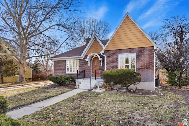 view of front of home with brick siding, a chimney, a front yard, and central air condition unit