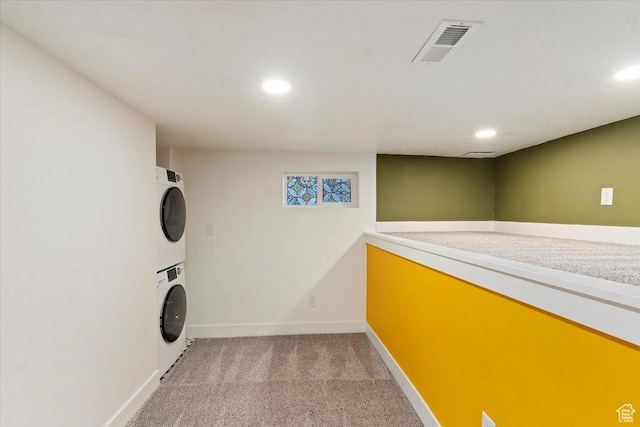 washroom with laundry area, baseboards, visible vents, stacked washer / dryer, and light colored carpet