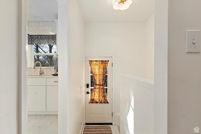 doorway with marble finish floor and a sink