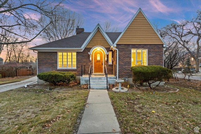 view of front of property with a yard, a chimney, and brick siding