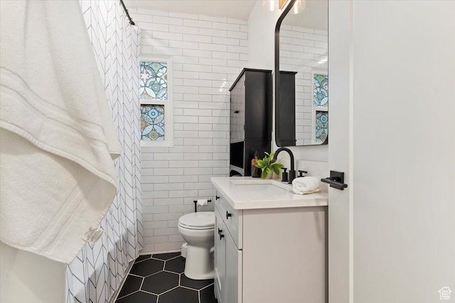 full bath with toilet, tile patterned flooring, tile walls, and vanity