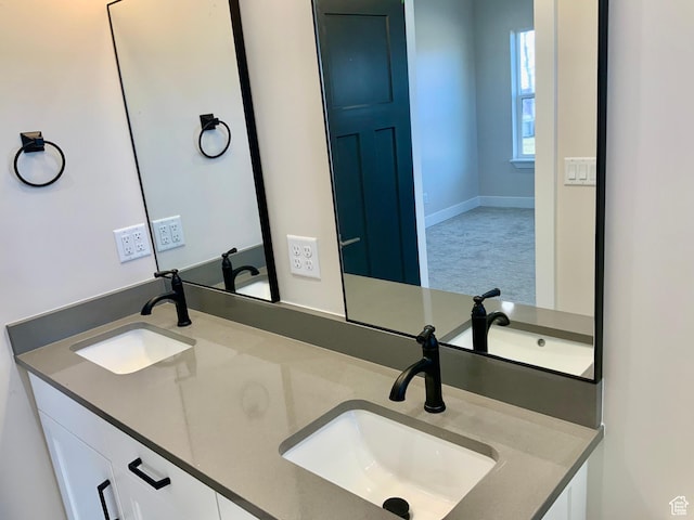 bathroom with a sink, baseboards, and double vanity