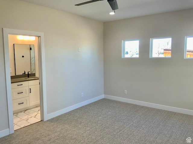 unfurnished bedroom with light carpet, multiple windows, baseboards, and a sink