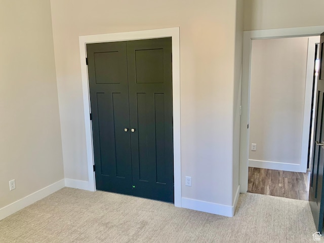 unfurnished bedroom featuring light carpet, a closet, and baseboards