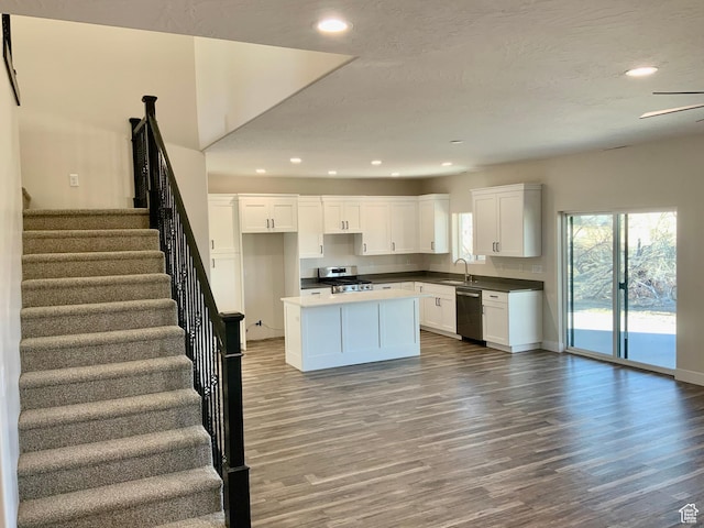 kitchen featuring a center island, appliances with stainless steel finishes, white cabinetry, a sink, and wood finished floors