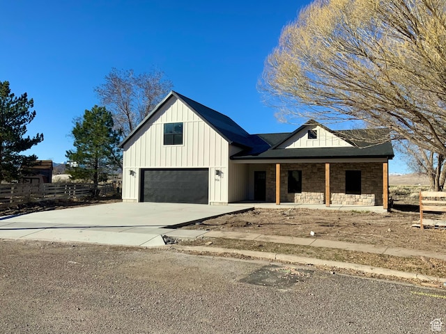 modern inspired farmhouse with board and batten siding, concrete driveway, fence, and stone siding