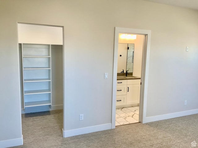 unfurnished bedroom featuring light carpet, a closet, a walk in closet, and baseboards