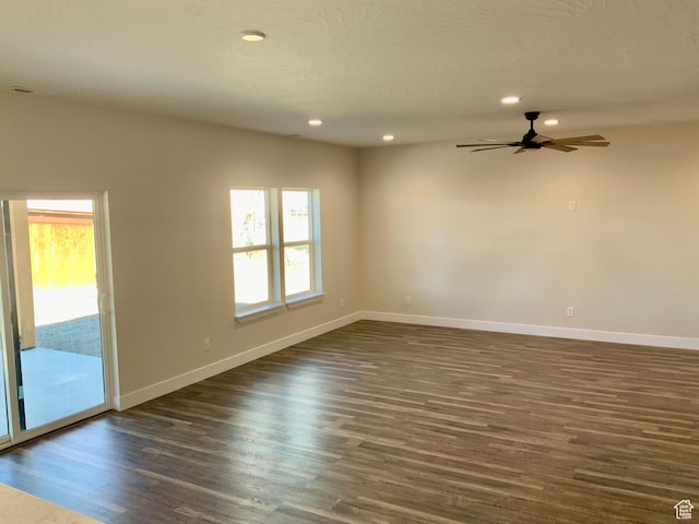 spare room featuring dark wood-style flooring, recessed lighting, and baseboards
