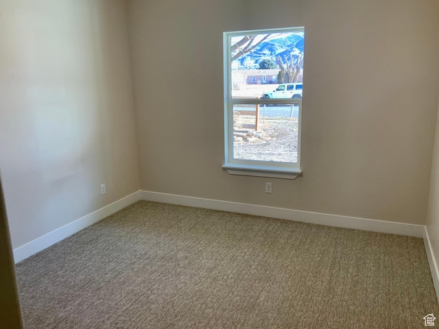 carpeted empty room featuring baseboards