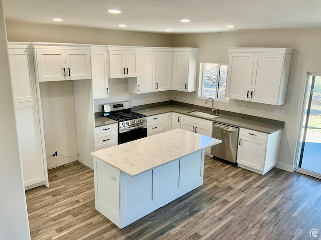 kitchen with stainless steel appliances, a kitchen island, a sink, white cabinets, and plenty of natural light