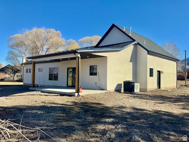 back of house with stucco siding, cooling unit, and a patio