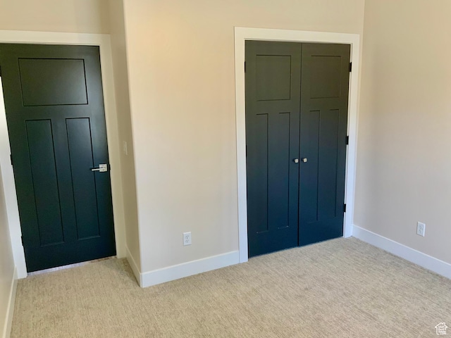 unfurnished bedroom featuring light carpet, a closet, and baseboards
