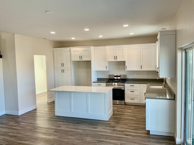 kitchen with stainless steel gas stove, a kitchen island, dark wood finished floors, and white cabinets