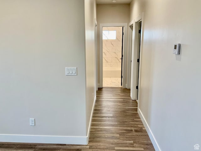 hall with dark wood-style flooring and baseboards
