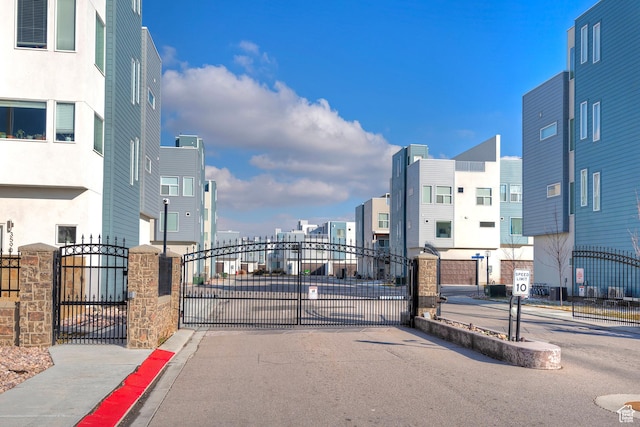view of street featuring a gate, sidewalks, curbs, and a gated entry