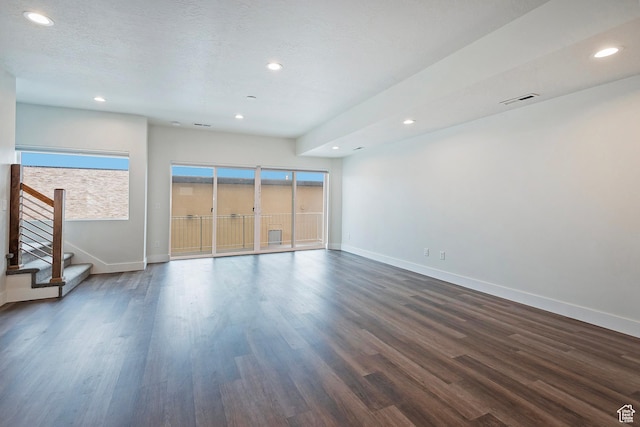 interior space with dark wood-type flooring, visible vents, a textured ceiling, and baseboards