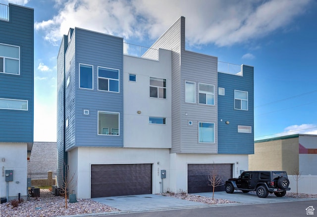 view of front facade featuring driveway, a garage, central AC unit, and stucco siding