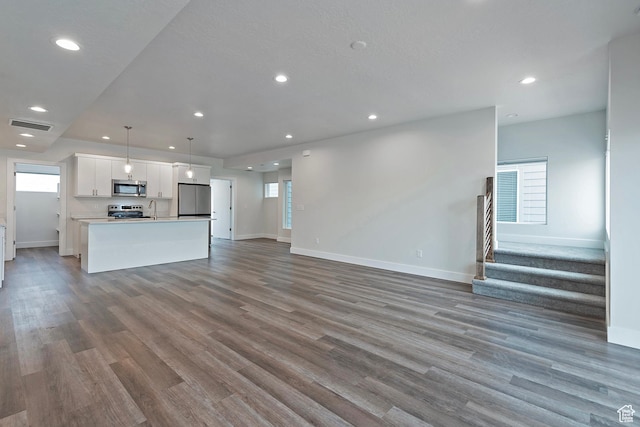 unfurnished living room with recessed lighting, wood finished floors, visible vents, and stairs