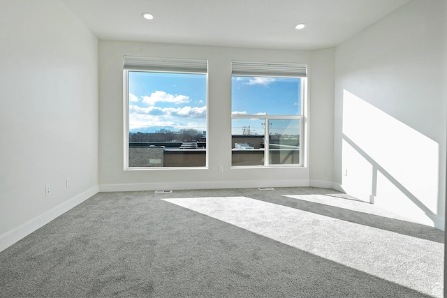 spare room featuring a healthy amount of sunlight, carpet, baseboards, and recessed lighting