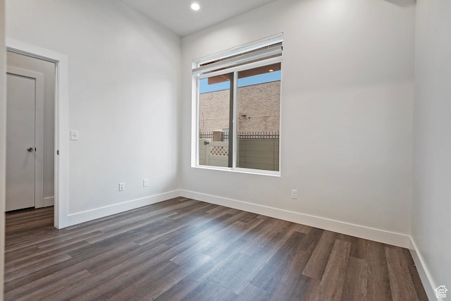 spare room with baseboards, dark wood-style flooring, and recessed lighting