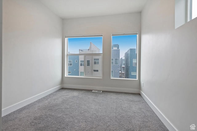 spare room with carpet floors, baseboards, visible vents, and a city view