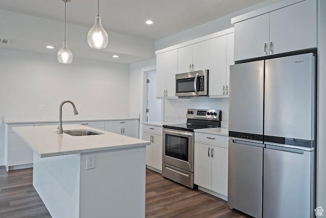 kitchen with appliances with stainless steel finishes, a sink, a center island with sink, and white cabinetry