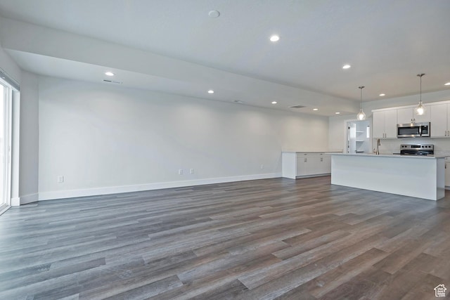 unfurnished living room with dark wood-type flooring, recessed lighting, visible vents, and baseboards