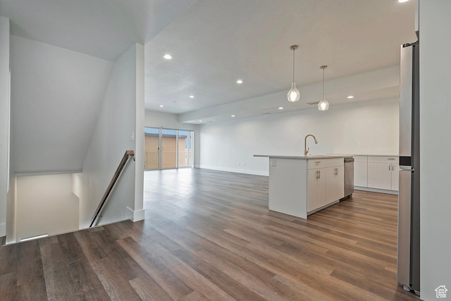 kitchen featuring a center island with sink, open floor plan, dark wood-type flooring, light countertops, and white cabinetry
