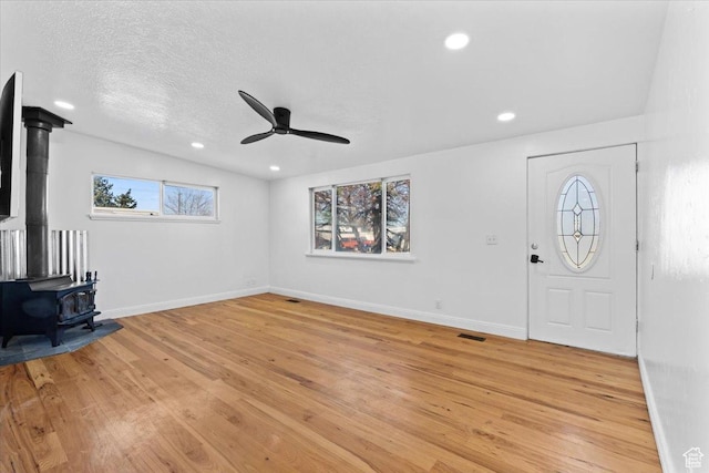 6357 W 3570 S, West Valley City, UT 84128 - unfurnished living room with light wood finished floors, a wood stove, ceiling fan, a textured ceiling, and baseboards
