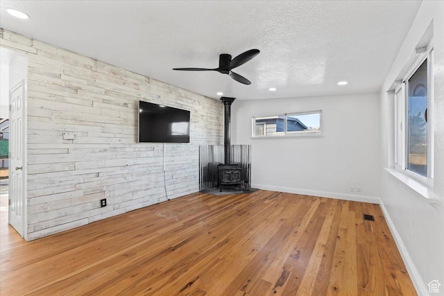 6357 W 3570 S, West Valley City, UT 84128 - unfurnished living room with a textured ceiling, visible vents, baseboards, wood-type flooring, and a wood stove